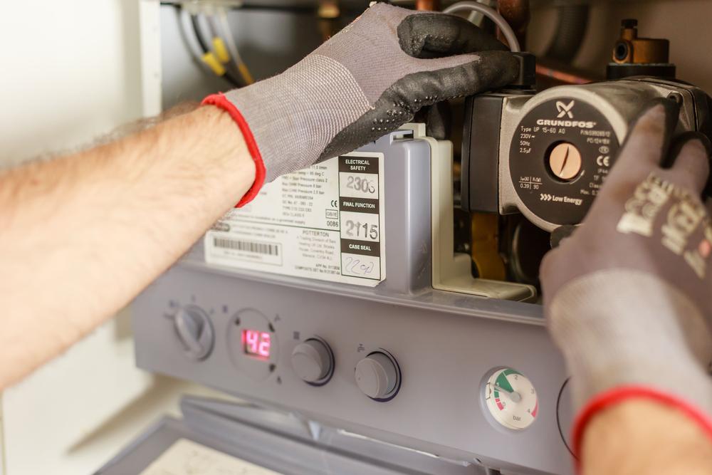 Mains gantées qui règlent le circulateur d'une chaudière