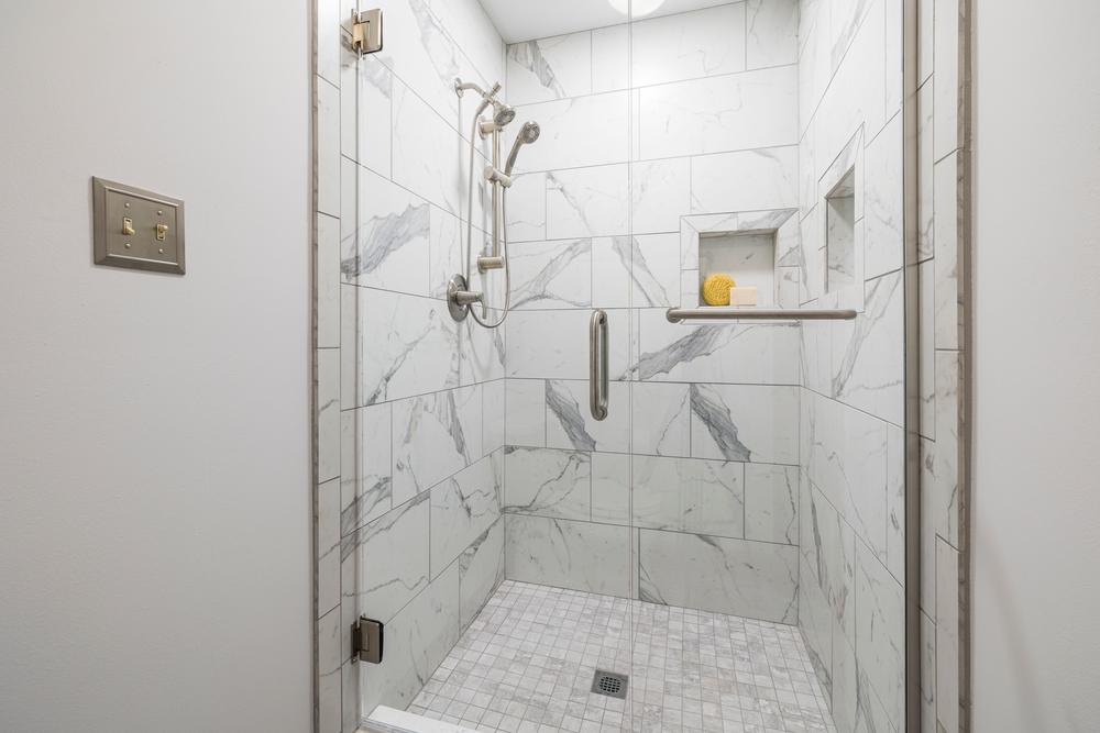 Salle de bain avec douche en marbre blanc et porte vitrée